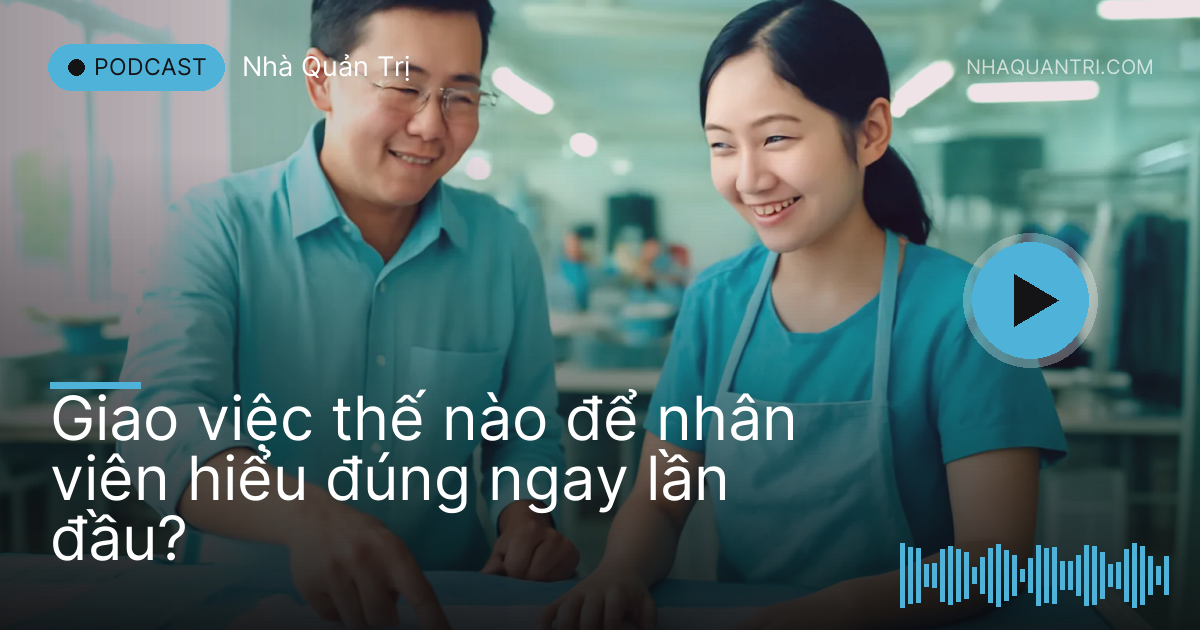 Anh quản lý và cô nhân viên đứng cạnh bàn cắt vải trong xưởng may sáng