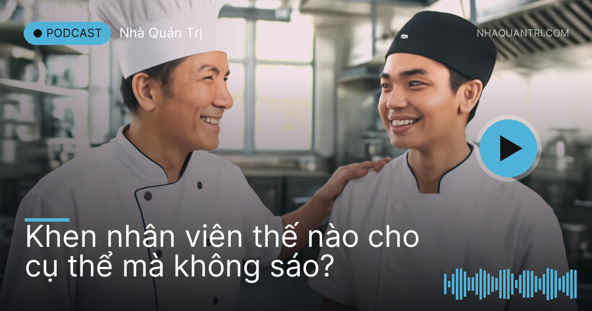 Anh bếp trưởng vỗ vai phụ bếp trẻ trong bếp nhà hàng inox sáng