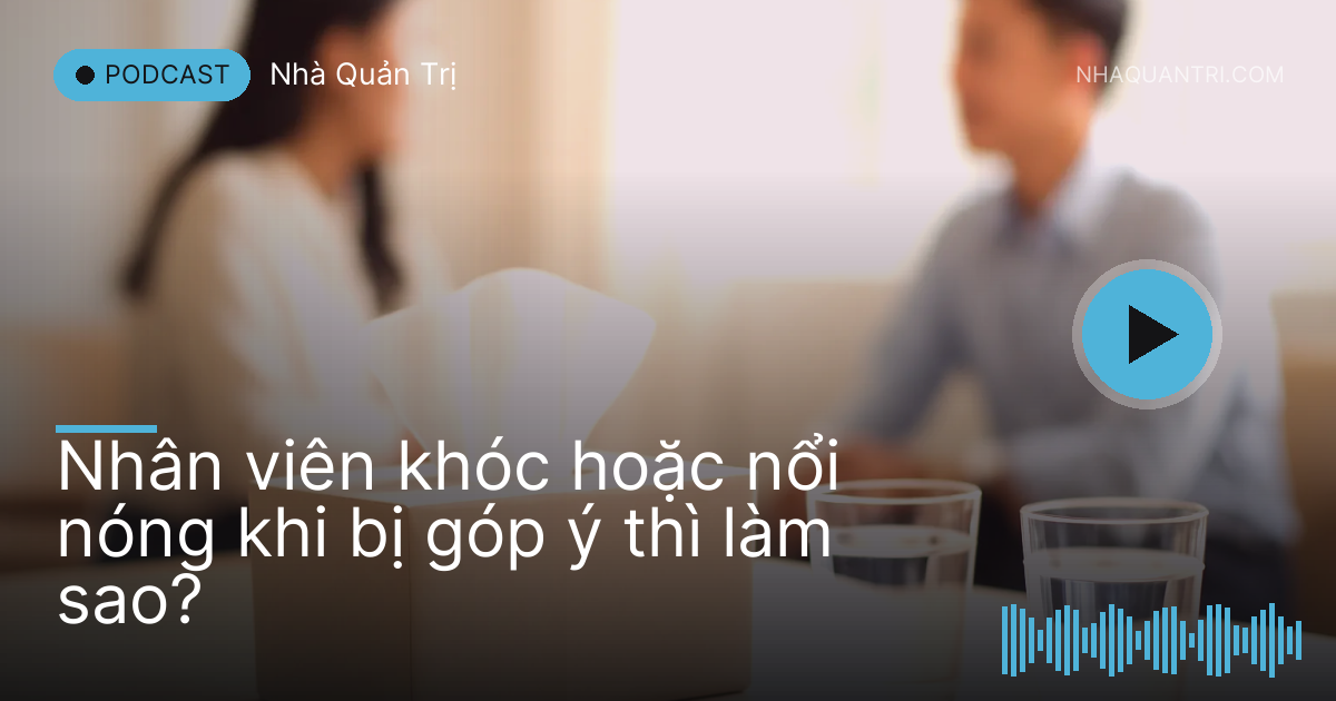 Hộp khăn giấy và hai cốc nước trên bàn họp nhỏ, hai bóng người mờ phía sau